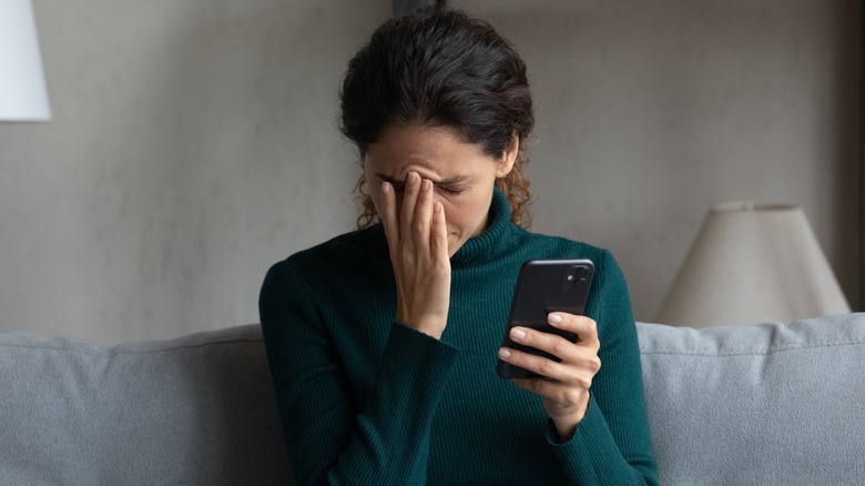 Person holding phone looks upset