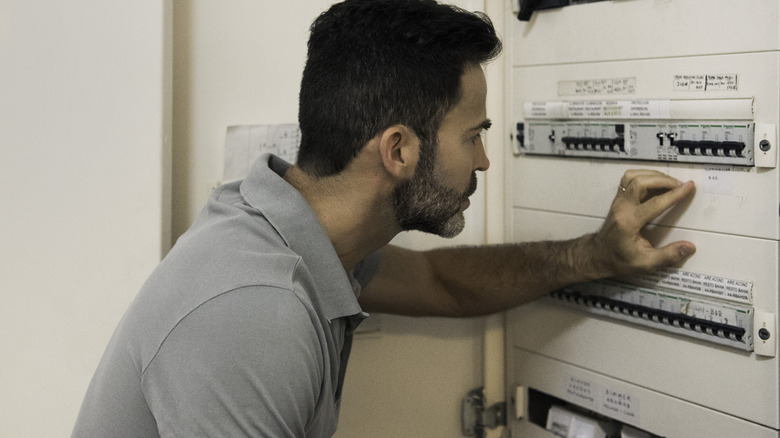 Man looking at an open electrical panel in a home