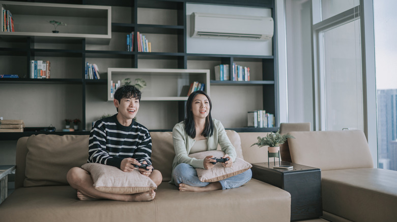 A couple playing a video game in a living room with AC