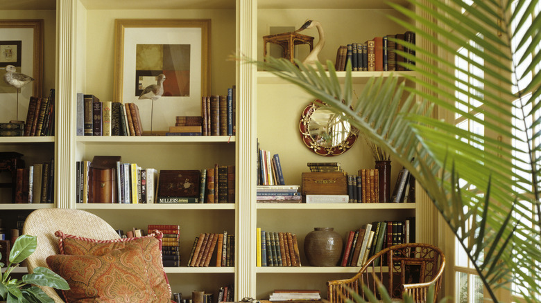 Shelf decorated with different books, mirror, photo frames and vases