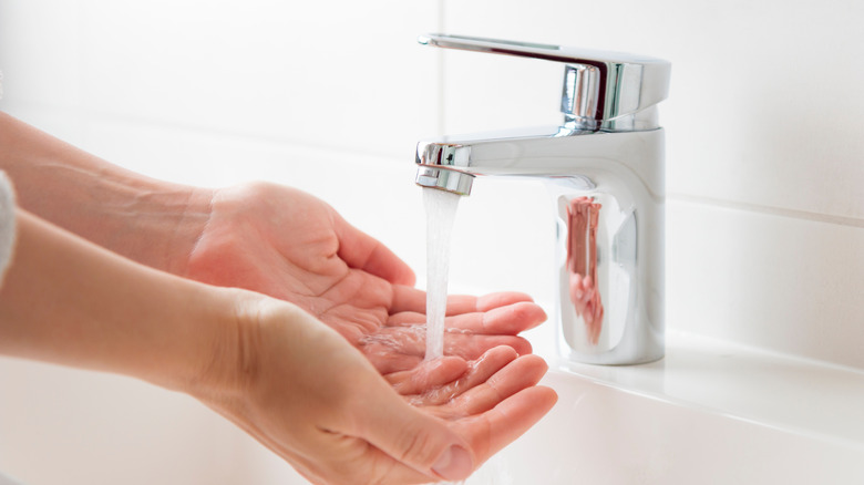 A person washing their hands under a faucet