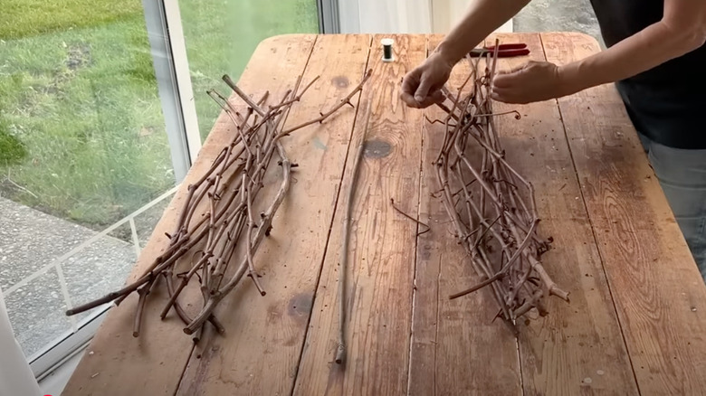 crafter using wire to tie together grapevine branches