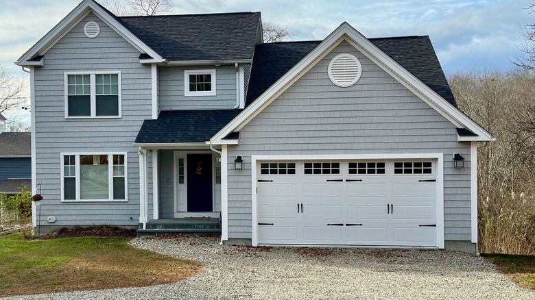 A grey house with a gravel driveway