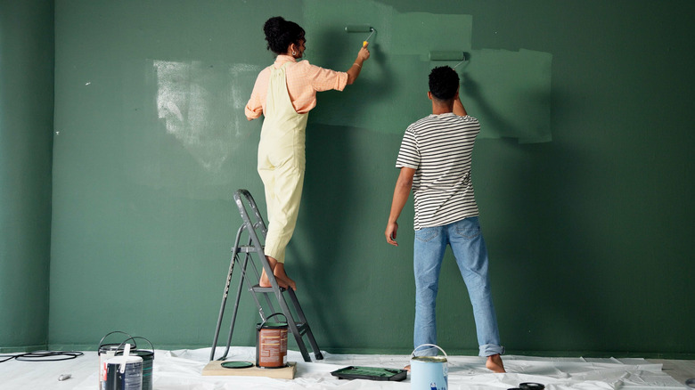 People painting a wall green