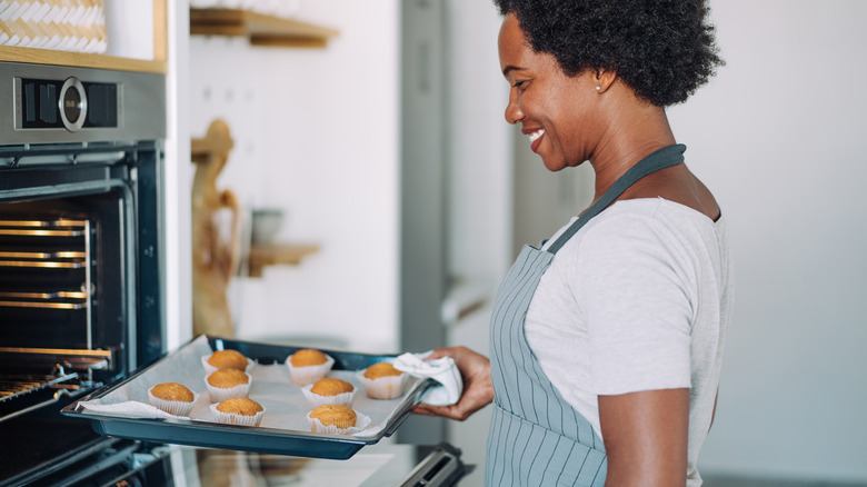 Woman taking muffins out of oven