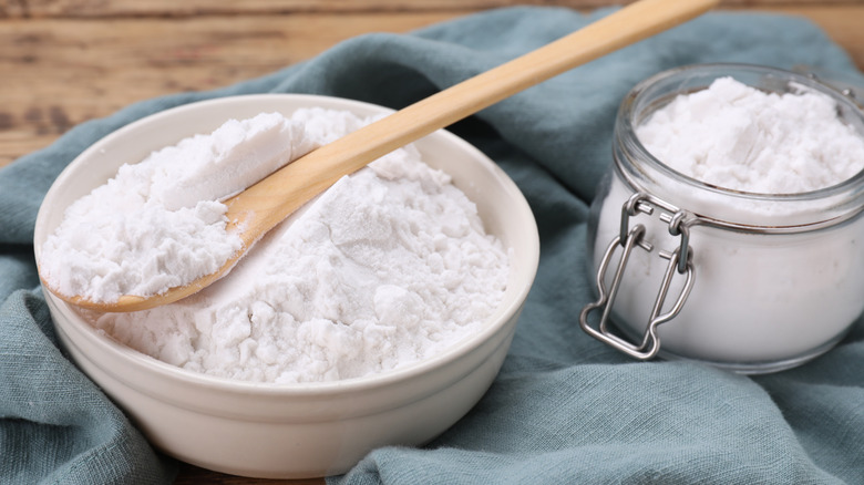 A bowl and jar of cornstarch with a wooden spoon