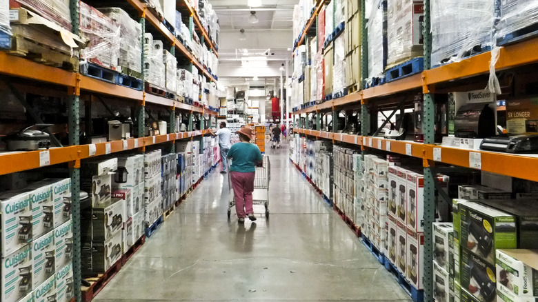 A woman in a blue shirt and pink slacks shops at Costco