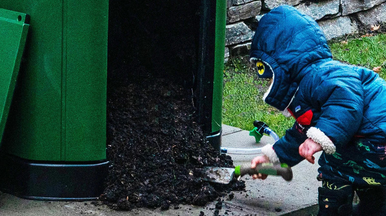 child shoveling compost from green bin