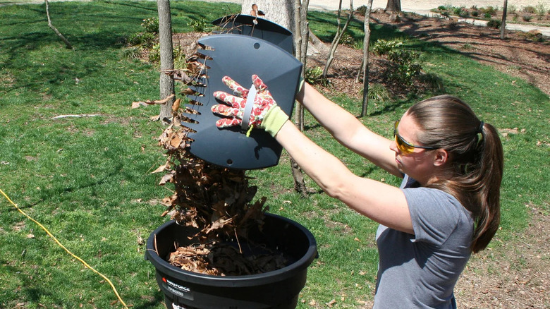 woman dumping leaves into leaf shredder