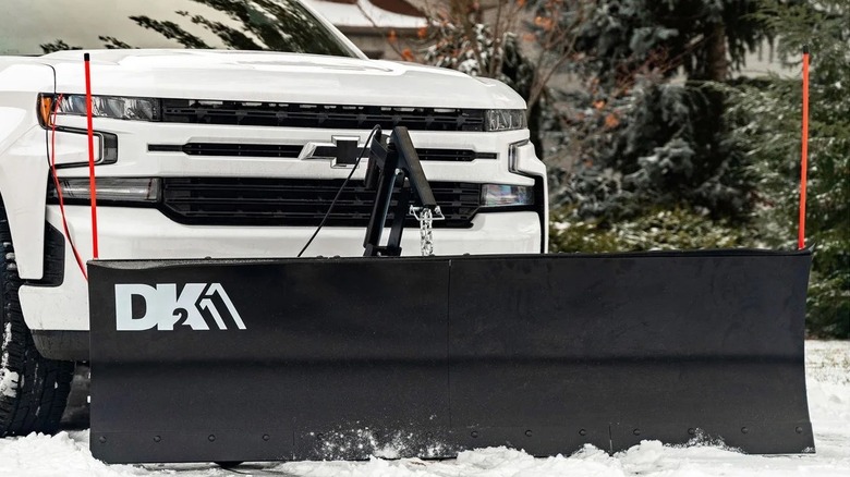 Large snow plow attached to the front of a pickup truck