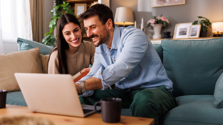 attractive couple smiling and browsing laptop together