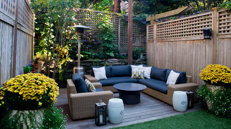 A walled backyard patio is decorated with seating and accessories