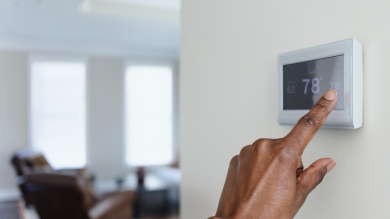 A person adjusting the thermostat