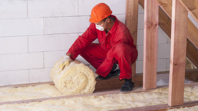 A worker adding insulation to an attic