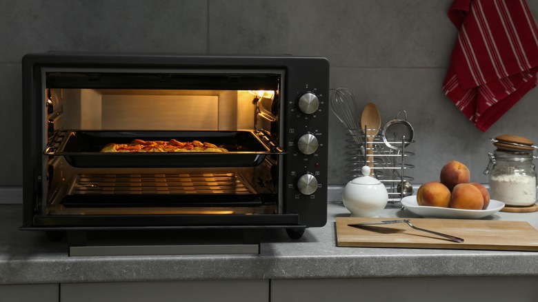 An electric oven on the countertop next to cutting board