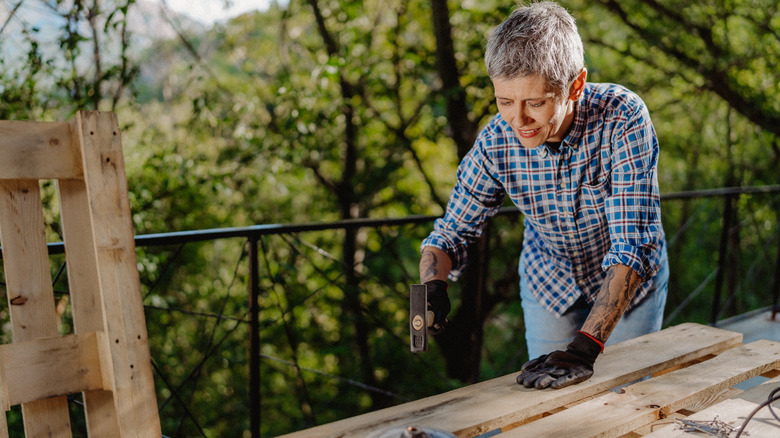 older woman working wood pallet