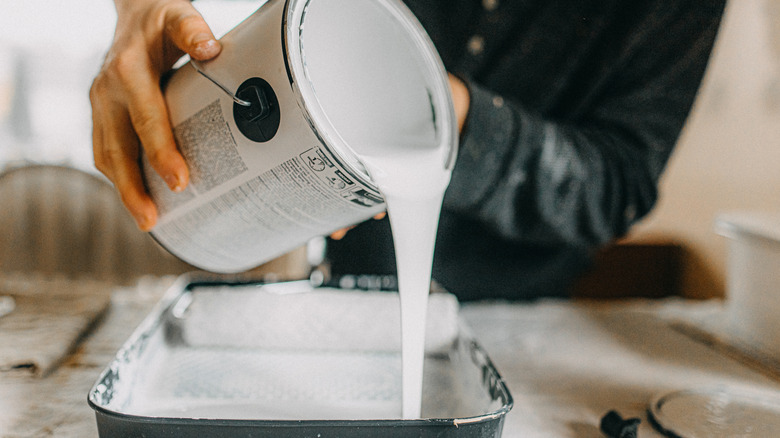 pouring paint from a can into a pan