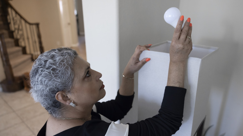 Woman changing lamp lightbulb