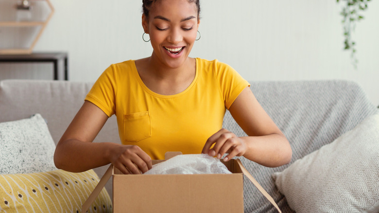 Woman smiling as she opens a cardboard box.