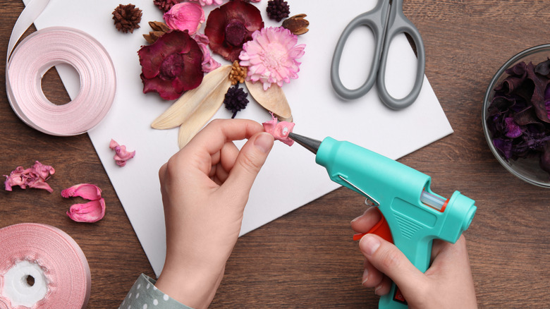 Person adding glue to flower pedal while creating floral DIY