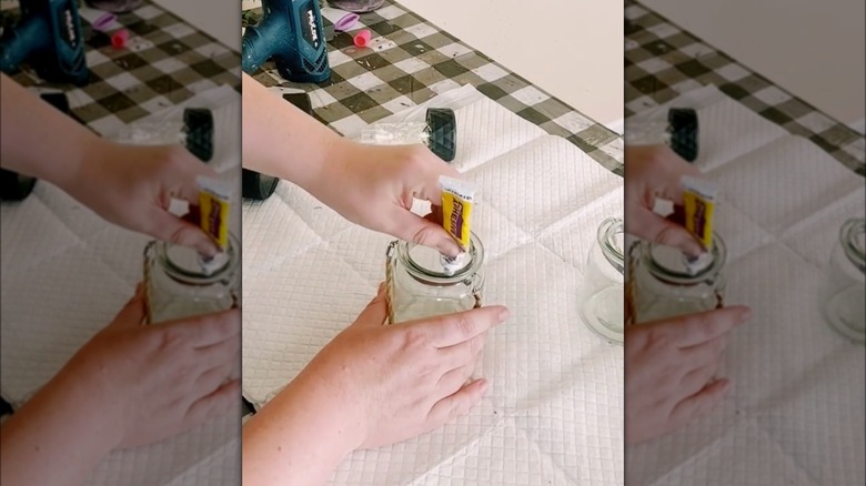 person adding glue to mason jar