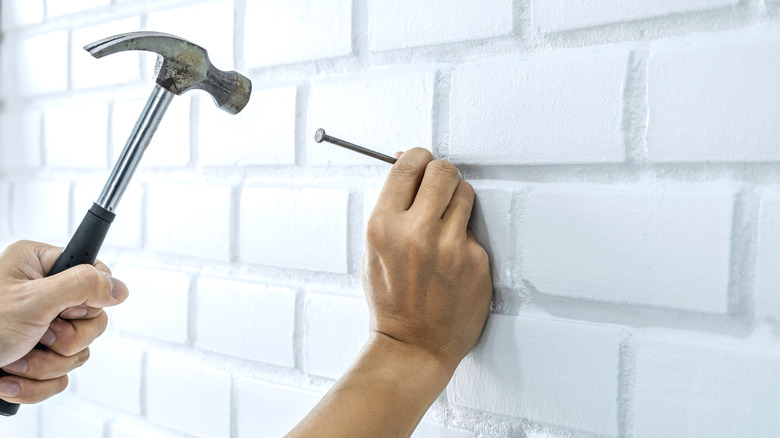 person hammering nail into wall