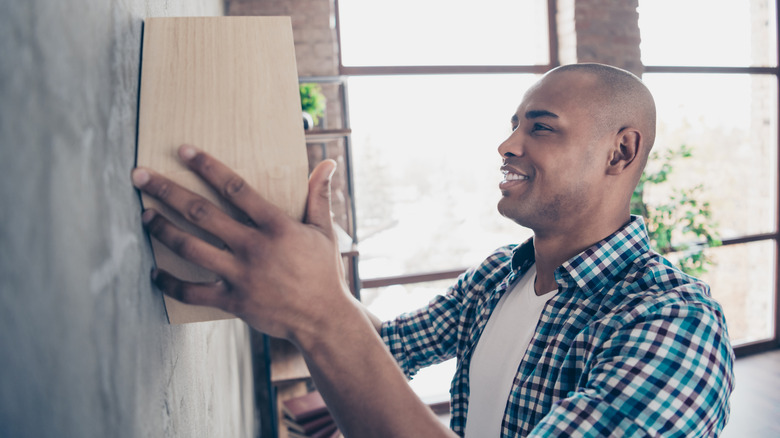 man hanging wooden shelf