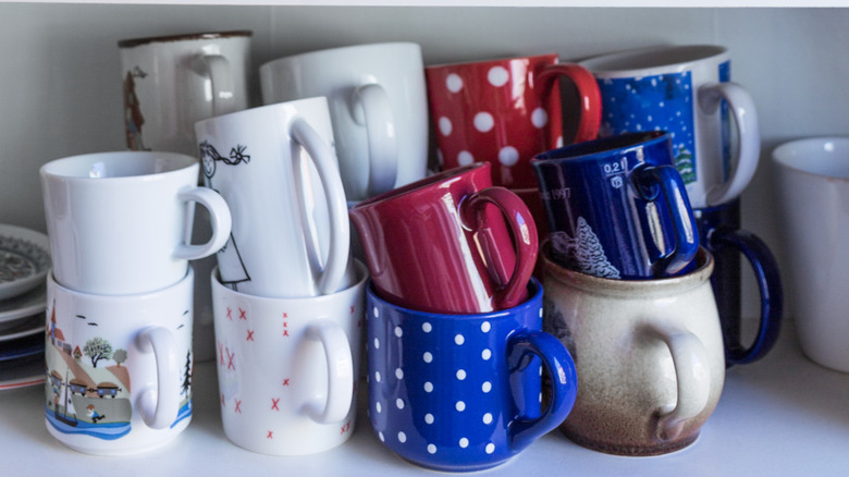 Pile of coffee mugs in kitchen cabinet