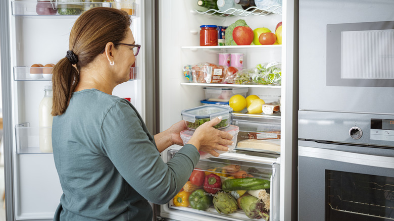 Woman placing her food in fridge