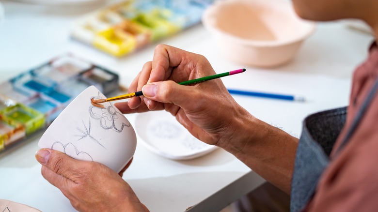 Person decorating mugs