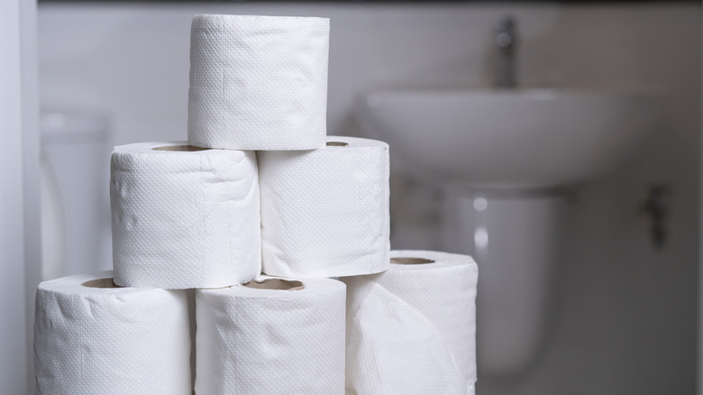 Toilet paper rolls stacked in a tower in a bathroom