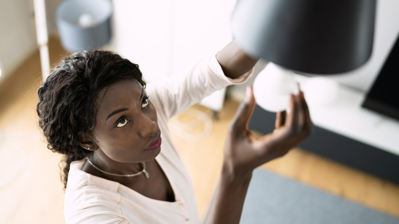 woman fixing light bulb