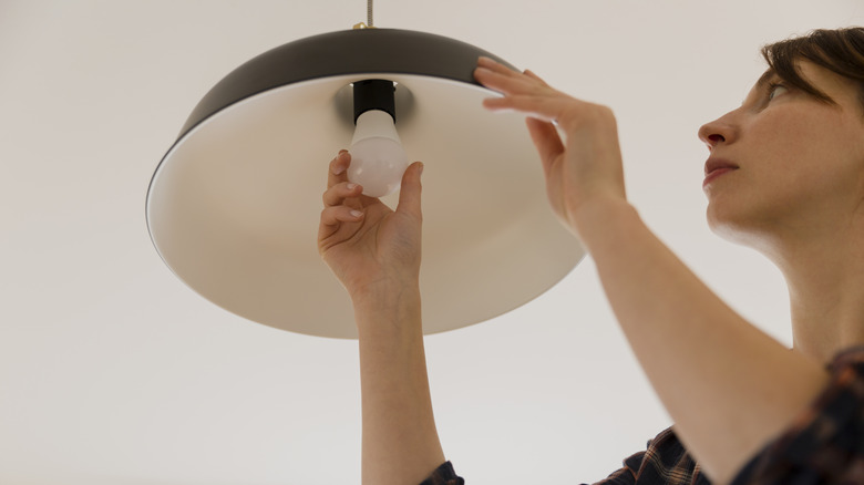 woman installing pendant light