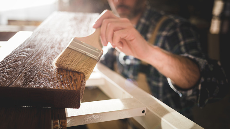 man staining wood plank