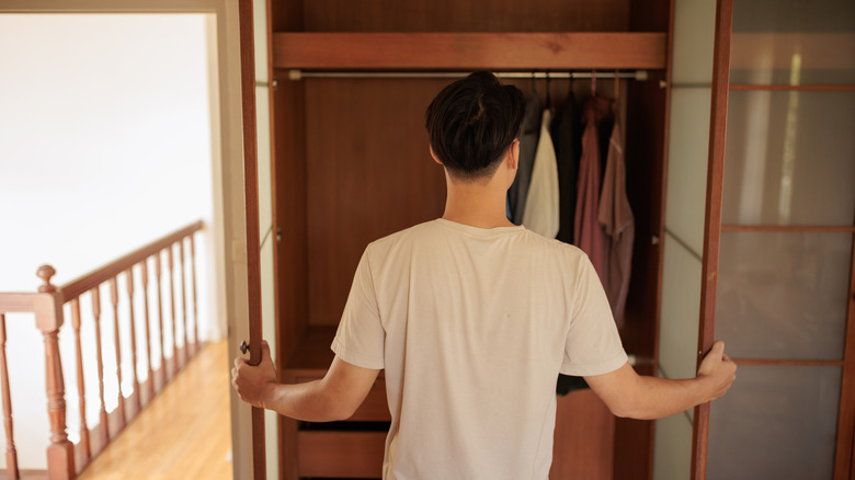 Man standing in front of an almost empty closet.