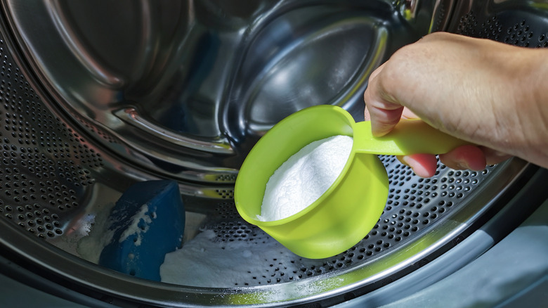 hand putting baking soda in washer