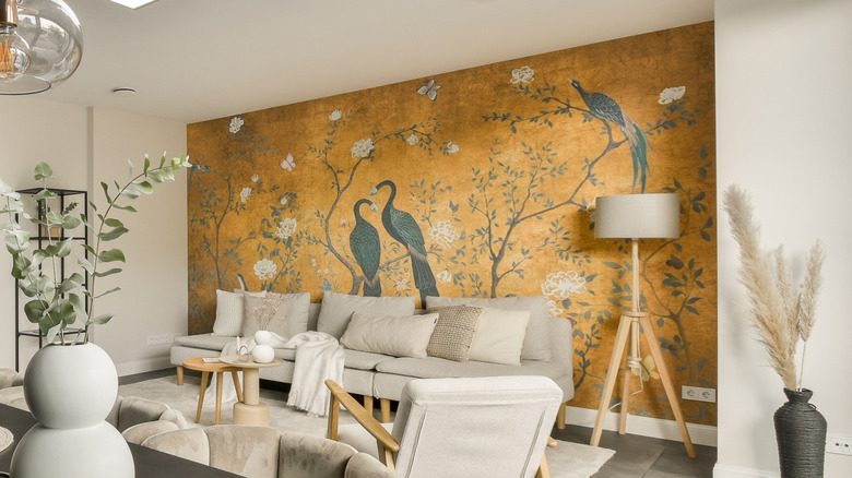 Wall mural of birds and trees in a living room with couches and other pieces of furniture