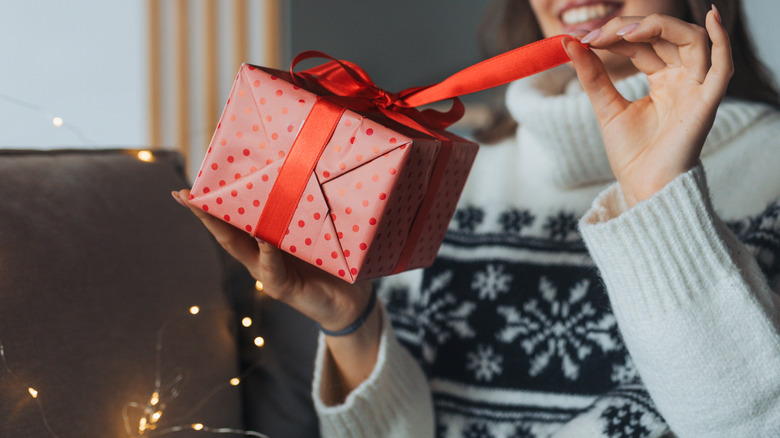 Woman unwrapping colorfully wrapped gift during holidays