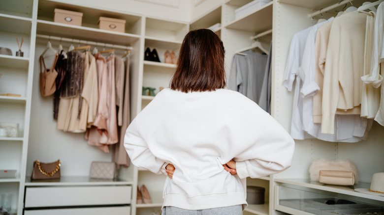 Woman with hands on her hips looking around her closet