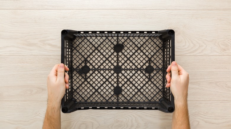 person holding black plastic crate