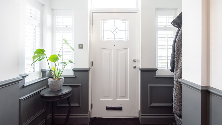 A home entryway with white door and potted plant on a side table.