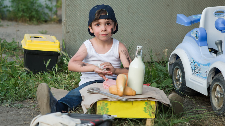 Boy drinking milk and fixing toy car