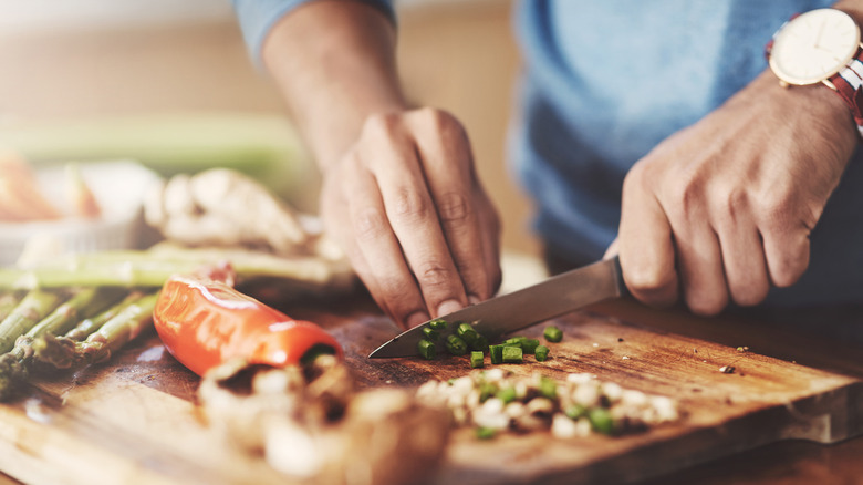 person chopping vegetables on cutting board