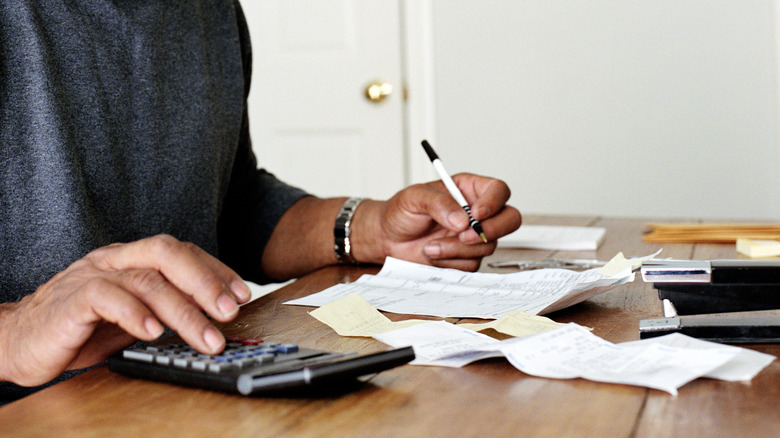 Person writing and using a calculator