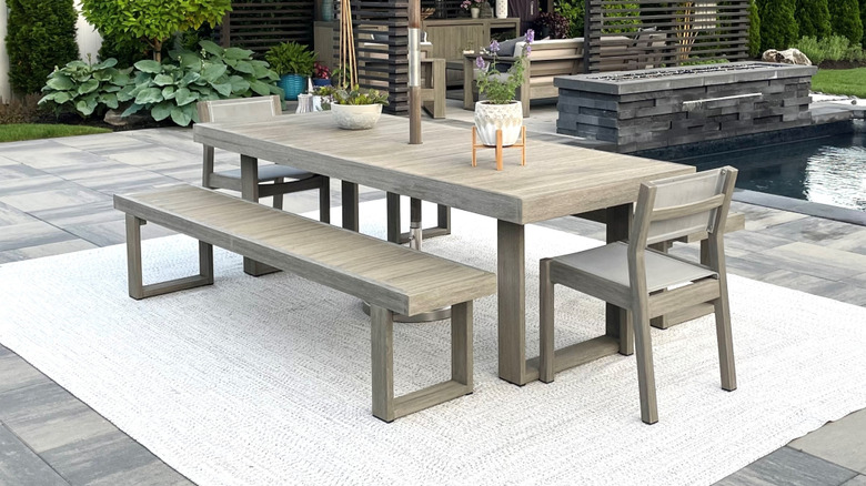 Gray patio with a table and outdoor rug underneath it.