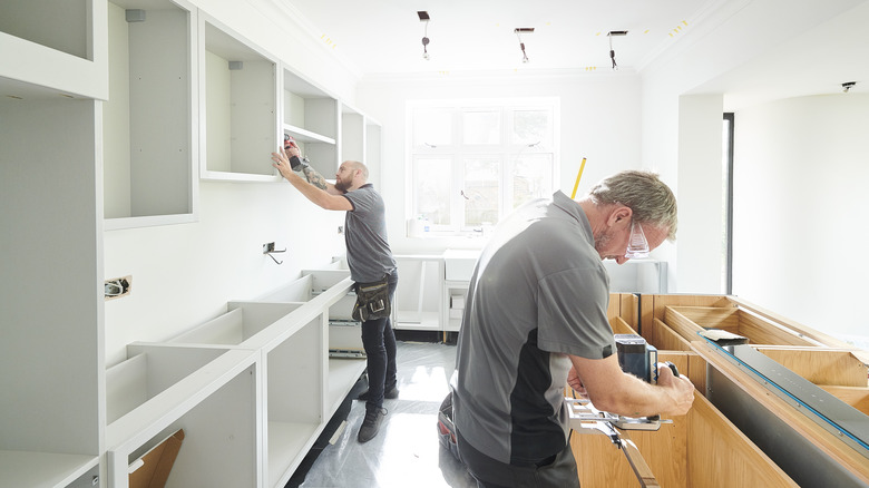two men installing kitchen cabinets