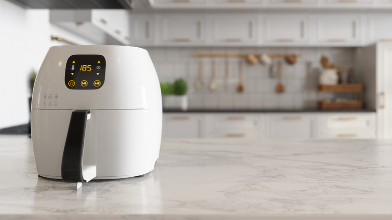 A small white air fryer sits on a white countertop