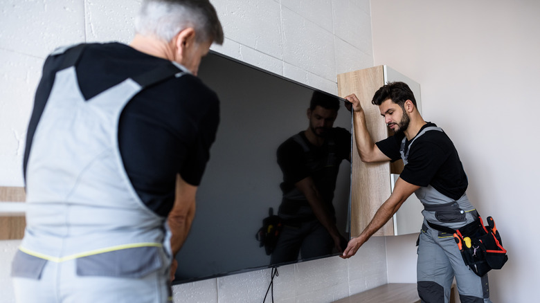 men lifting a TV off a bracket