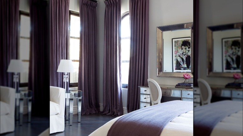 A luxurious bedroom with gray walls and dramatic wall-length purple curtains