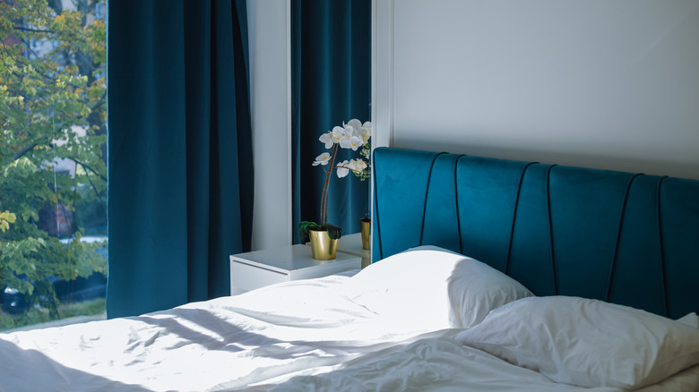 Bedroom with gray walls, white bedding, and deep blue curtains